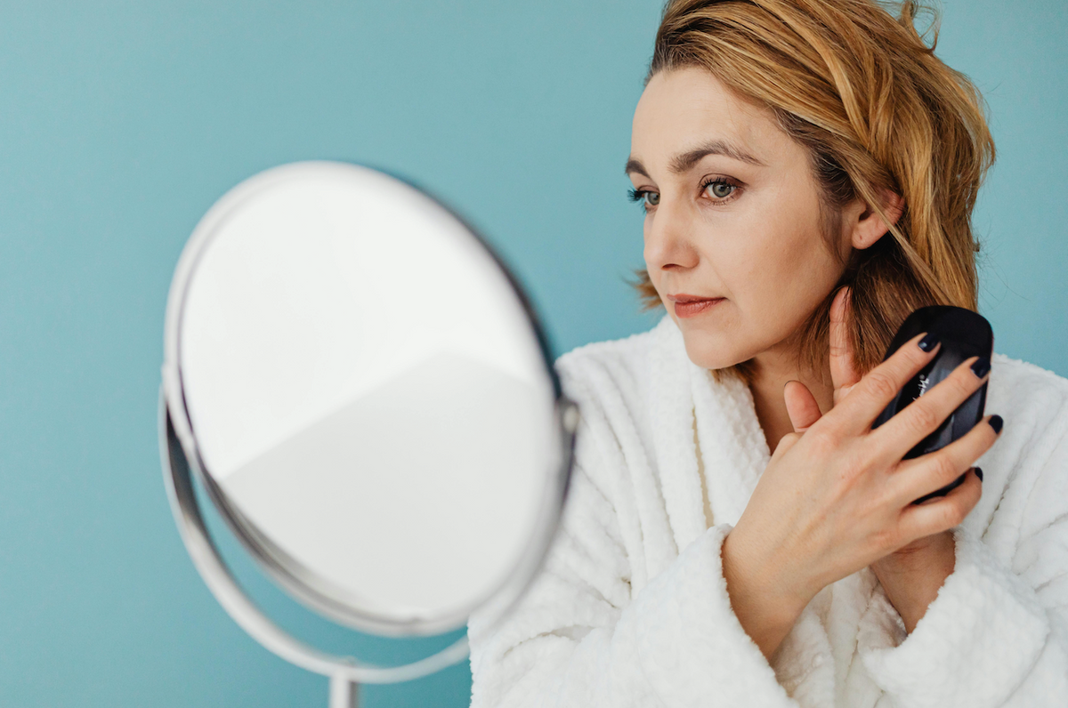 Woman examining hair changes in the mirror during menopause — the estrogen connection behind hair thinning after 40