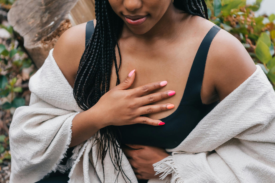 Woman in her 40s sitting with her hand near her chest, reflecting on heart palpitations during menopause