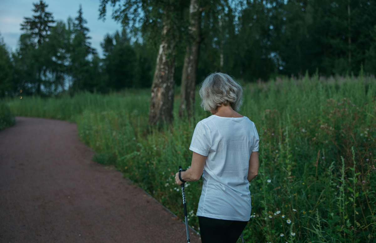 Woman walking on a nature path with walking poles representing an active approach to understanding menopause-related weight gain and metabolic changes